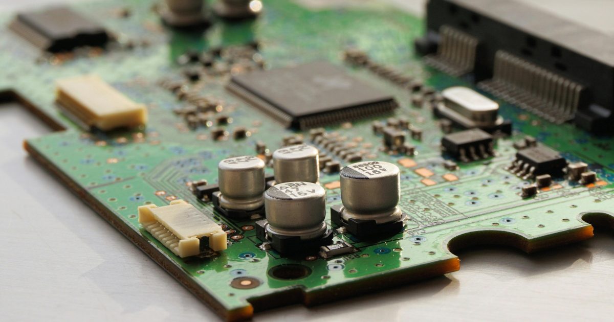 Detailed view of a green circuit board featuring capacitors and microchips.