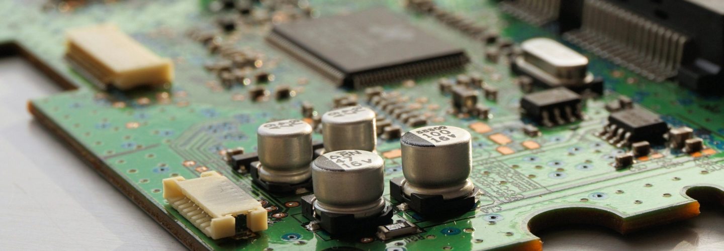Detailed view of a green circuit board featuring capacitors and microchips.