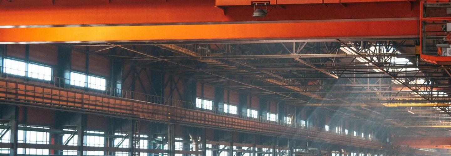 Spacious factory interior featuring large overhead cranes and metal walkways.