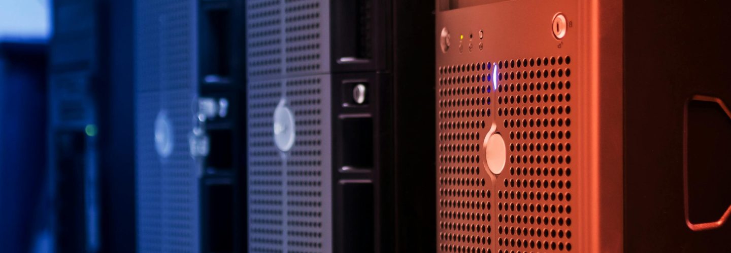Close-up of tower servers in a data center with blue and red lighting.