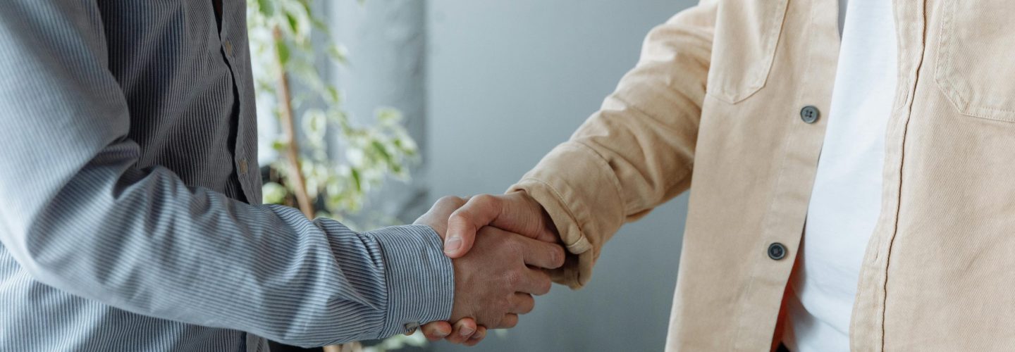A close-up image of two businesspeople shaking hands in an office environment symbolizing agreement and partnership.